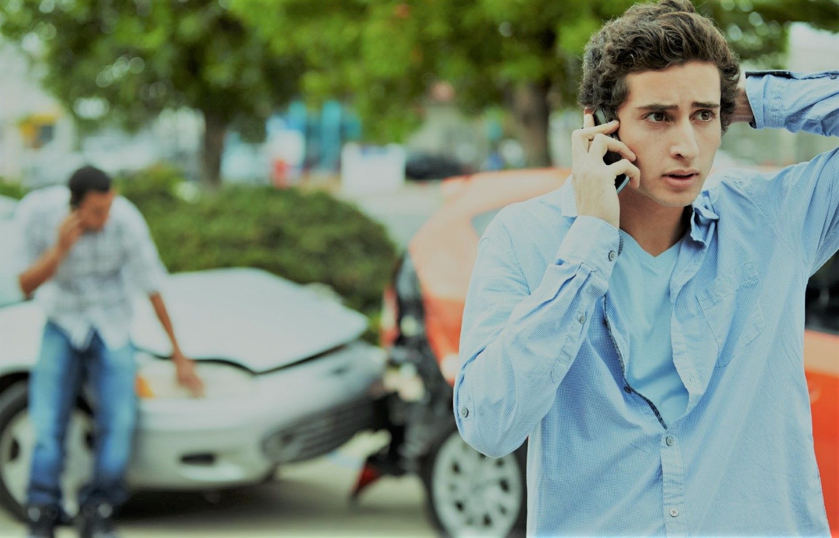 young man on cell phone at the scene of a car accident